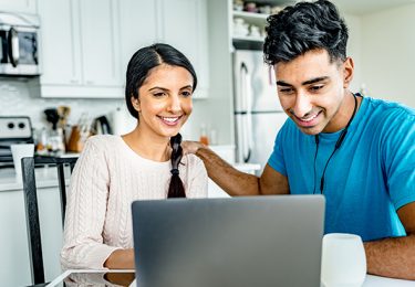 Young Indian couple working on home budget. View of the modern penthouse apartment in the background.