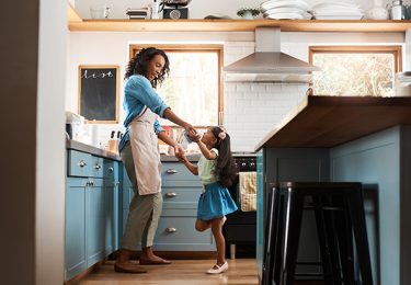 Shot of a young woman dancing with her daughter in the kitchen at home